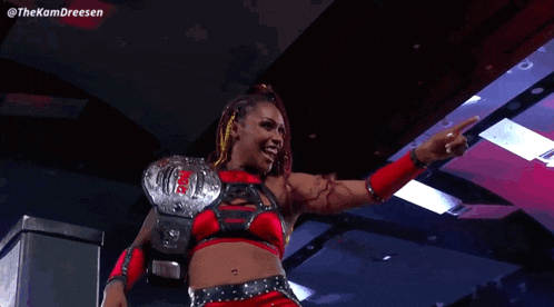 a female wrestler is wearing a championship belt and a red top