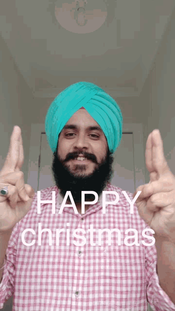 a man wearing a turban and a plaid shirt says " happy christmas "