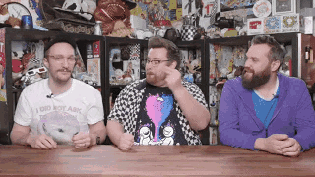 three men sitting at a table with one wearing a shirt that says " i did not ask "