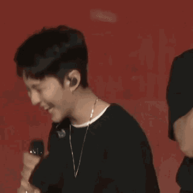a young man is laughing while holding a microphone in his hand .