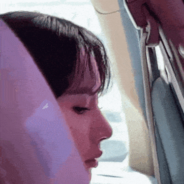 a close up of a woman 's face looking out a car window