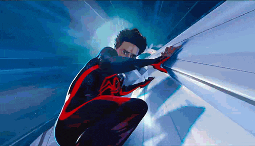 a man in a black and red spiderman costume is crawling on a wall