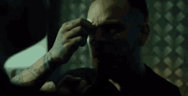 a man with a tattoo on his arm is getting a bandage on his face .