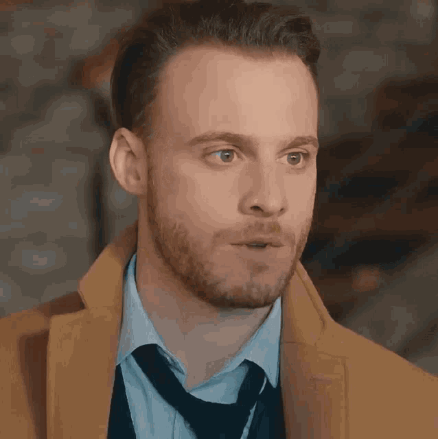 a man with a beard is wearing a yellow coat and tie