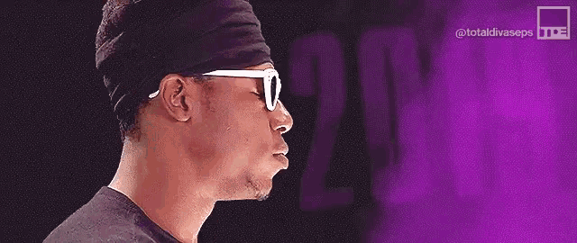 a man wearing sunglasses stands in front of a purple background with the year 2019
