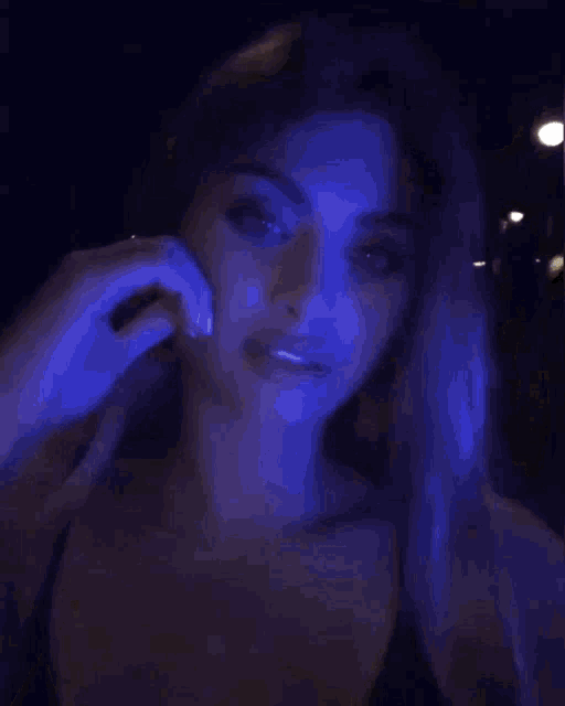 a woman is standing in a dark room with blue lights behind her .