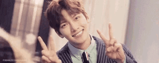 a man in a suit and tie is making a peace sign with his hands .