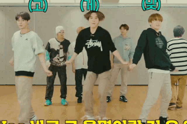 a group of young men are dancing and one of them is wearing a black stussy shirt
