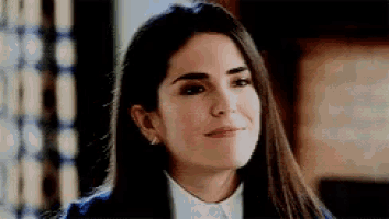 a woman with long hair is smiling and wearing a suit and white shirt .