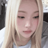 a close up of a woman 's face with long blonde hair and pink cheeks .
