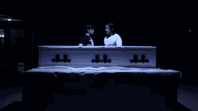 a white coffin with the lid open is lit up with blue light