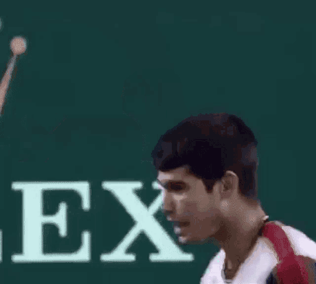 a man is swinging a tennis racket on a tennis court in front of a rolex sign .