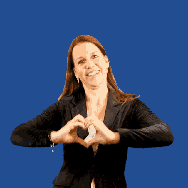 a woman in a black jacket making a heart with her hands