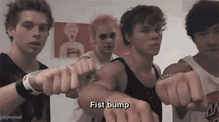 a group of young men are standing next to each other with their fists in the air and one of them says fist bump .