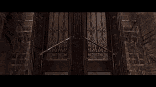 a dark room with a staircase leading up to a door with a wrought iron gate .