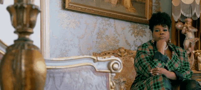 a woman in a green plaid jacket is sitting on a couch