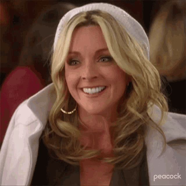 a woman wearing a white hat and earrings is smiling .