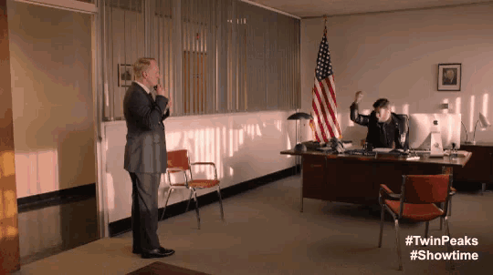 a man in a suit standing in front of an american flag in an office