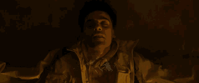 a man is laying down with his eyes closed in a dark room .