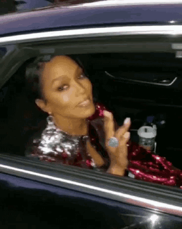 a woman is sitting in a car looking out the window and making a funny face .