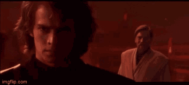 two men are standing next to each other in a dark room with a red light behind them .