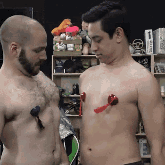 two shirtless men are standing next to each other with nipple clamps on their chests ..