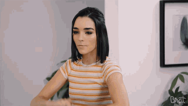 a woman in a striped shirt with the word brat on the bottom right