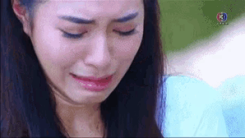 a close up of a woman crying with her eyes closed and her mouth open .