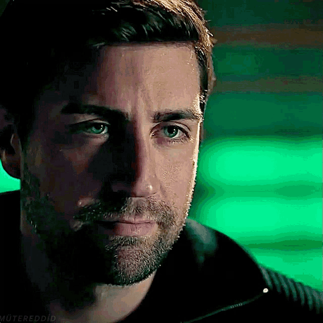 a close up of a man 's face with a green background and the words muteredd on the bottom right
