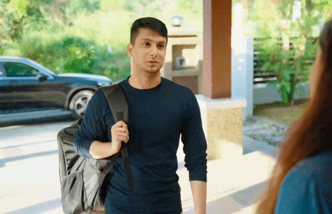 a man carrying a large black backpack stands in front of a black car