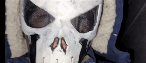 a person wearing a skull mask with a blue jacket