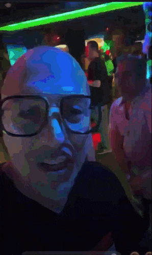a man wearing glasses and a blue mask is standing in a crowd