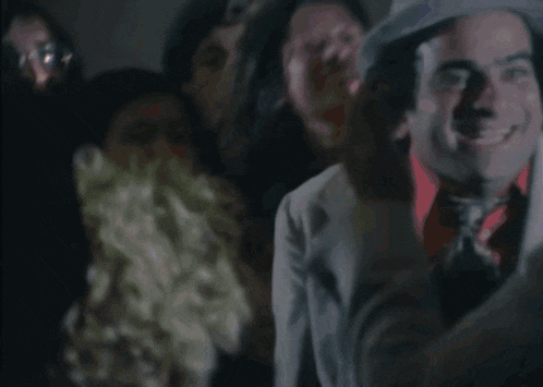a group of people are gathered in a dark room and one of them is holding a bouquet of flowers