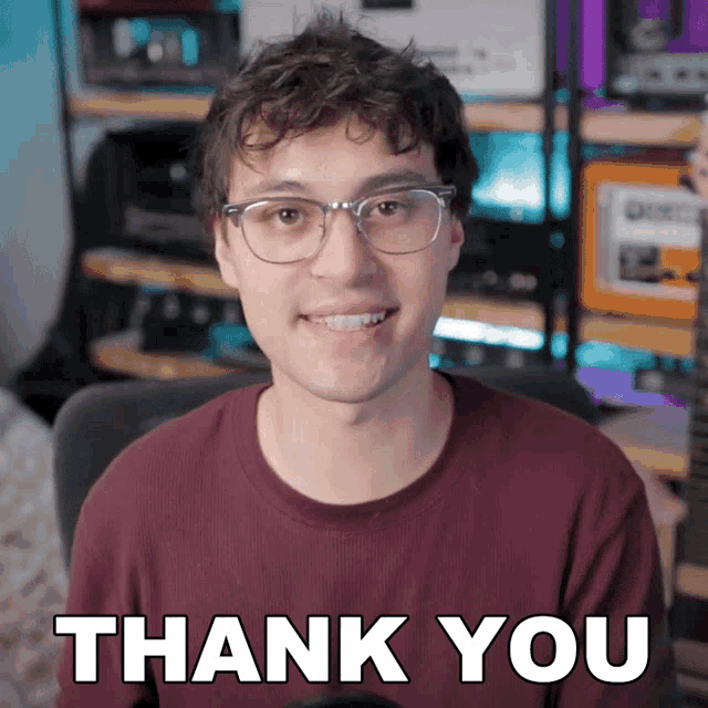 a man wearing glasses says thank you in front of a guitar
