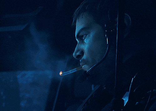 a man wearing a headset is smoking a cigarette in a dark room