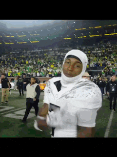 a football player wearing a helmet and gloves is standing on the field .