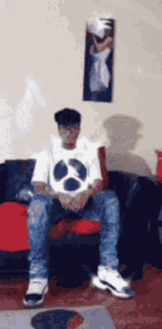 a young man is sitting on a couch in a living room .