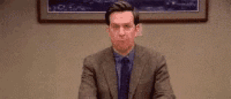 a man in a suit and tie is sitting at a desk in a room .