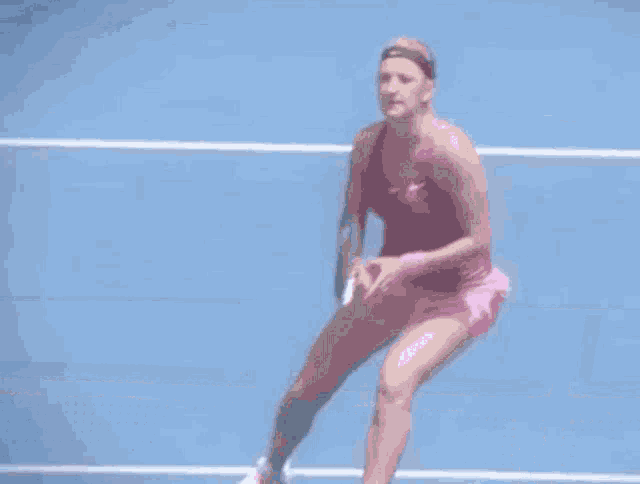 a woman in a pink dress is holding a tennis racquet on a tennis court