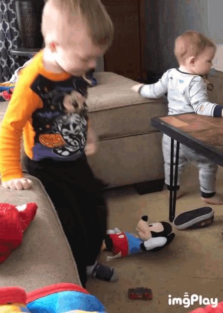 two young boys playing with a mickey mouse stuffed animal