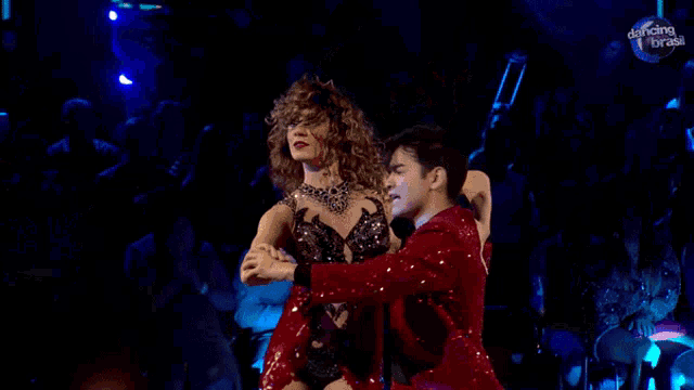 a woman in a red dress is dancing with a man in a red suit on dancing with the stars