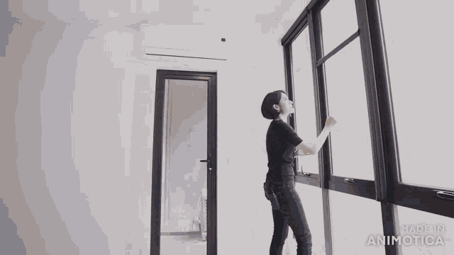 a woman stands in an empty room with the words made in animatica on the bottom right