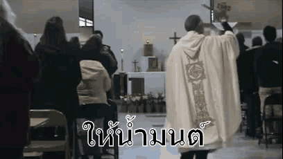 a priest is standing in front of a crowd of people in a church giving a sermon .