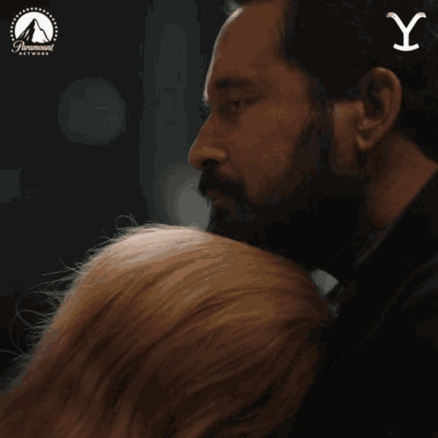 a man with a beard is hugging a woman with the letter y on his head