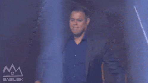 a man in a suit and a blue shirt is dancing in front of a sign that says basilisk