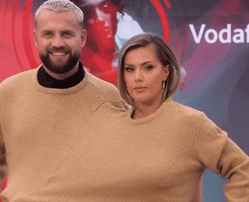 a man and a woman are posing for a picture in front of a sign that says voda