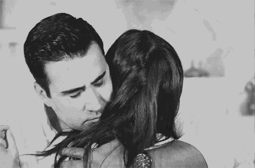 a black and white photo of a man hugging a woman .