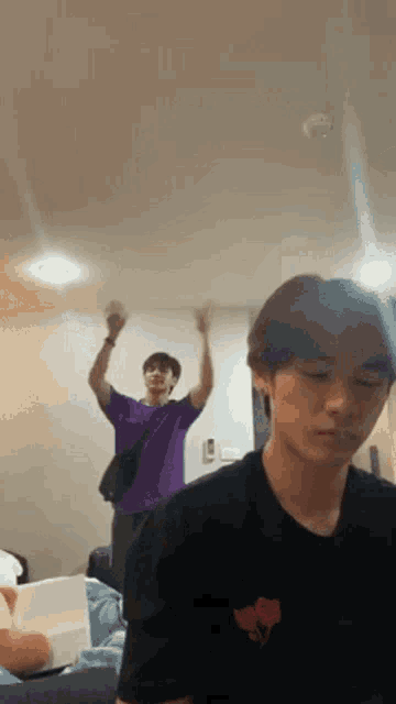 a man in a purple shirt is standing next to another man in a black shirt in a room .