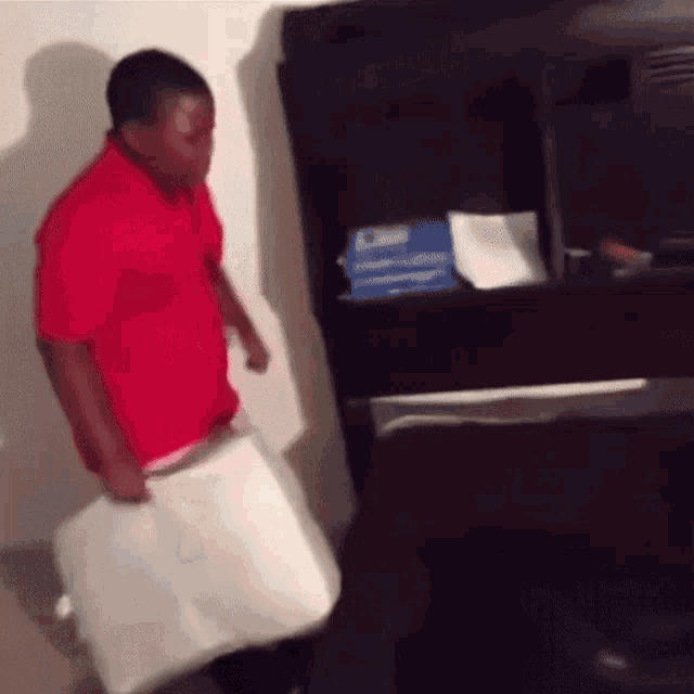a man in a red shirt is carrying a white bag