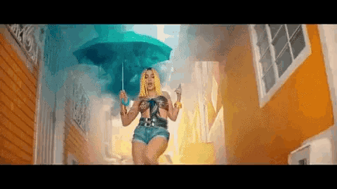 a woman is holding an umbrella in the rain while walking down a street .